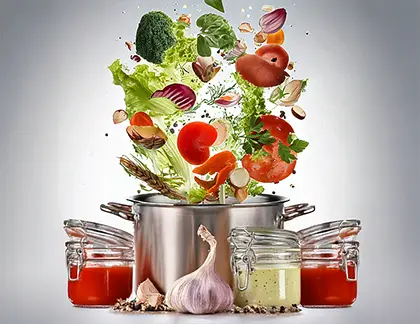 Whole food ingredients falling into pot for homemade sauce